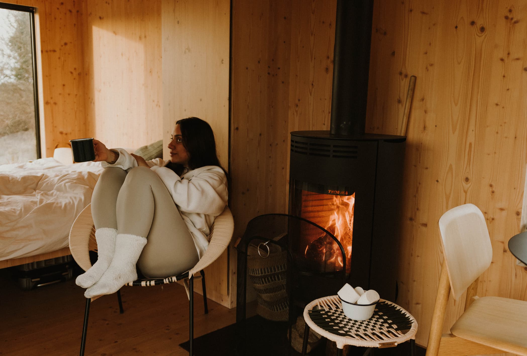 woman drinking tea by a fire in a cabin